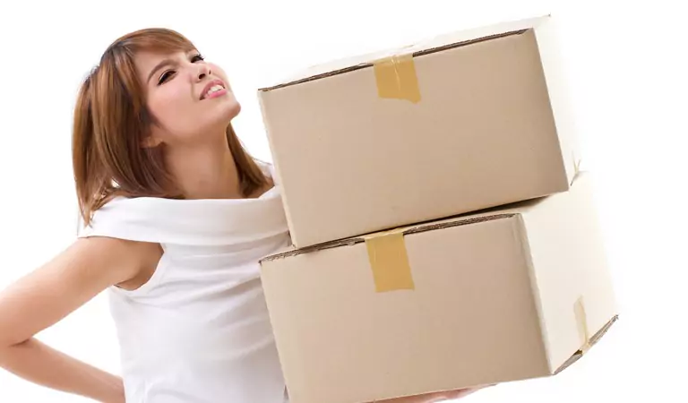 woman looking in pain and holding a couple of cardboard boxes