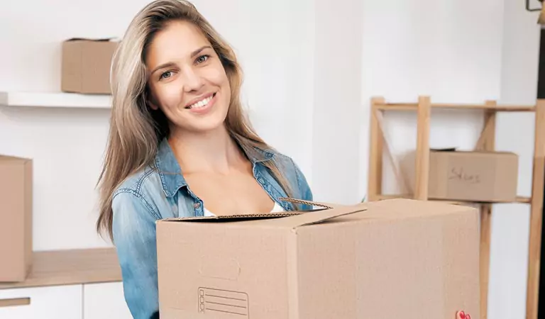 Smiling woman holding a cardboard box in hands