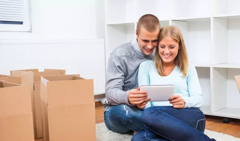 couple sitting on the floor and watching something on a phone