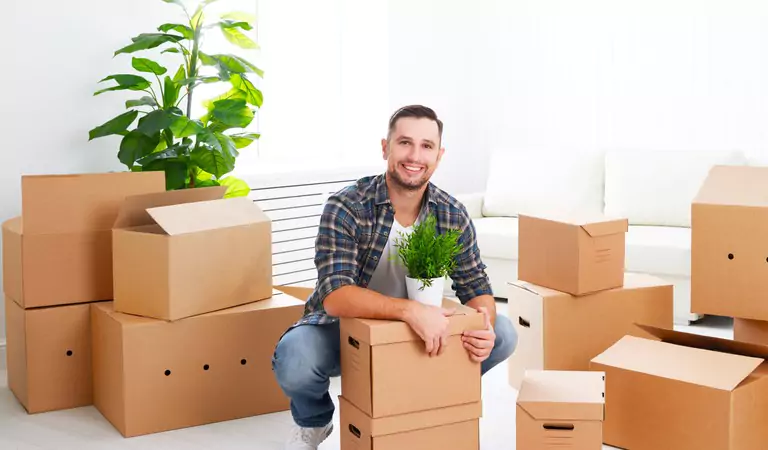 young man sitting on the floor and surrounded by the cardboard boxes