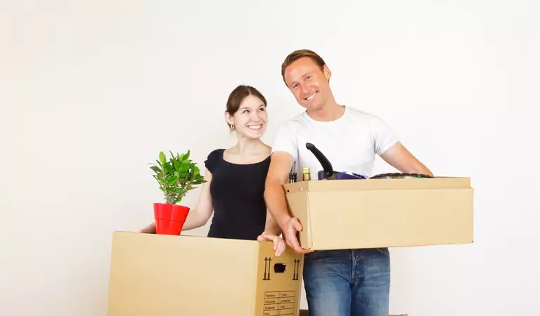young man and a woman holding boxes in hands inside of a house
