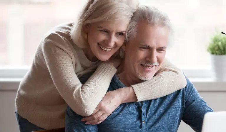 old age couple looking happy and searching for something on a laptop