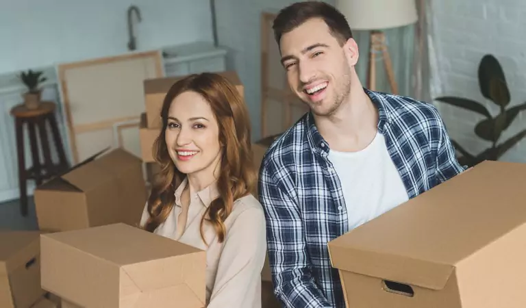 happy couple with cardboard boxes into a new house
