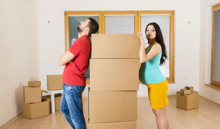young man and a pregnant women standing with some cardboard boxes