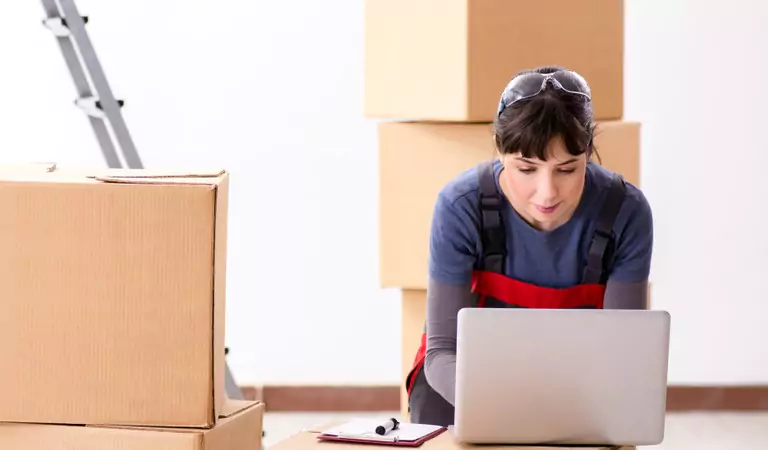 young girl working on a laptop and some cardboard boxes at the back