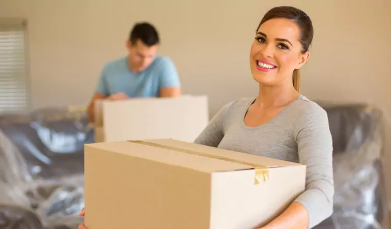 couple with cardboard boxes inside of a new house