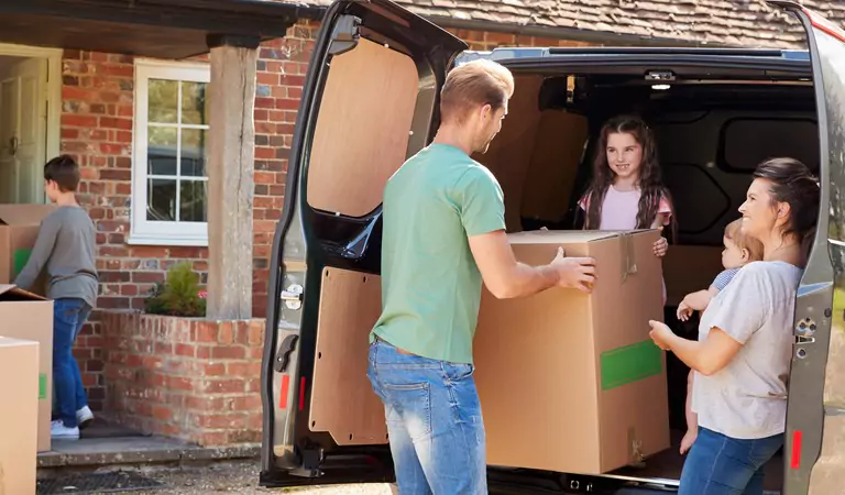 young man an a young girl trying to unload a heavy box from a van