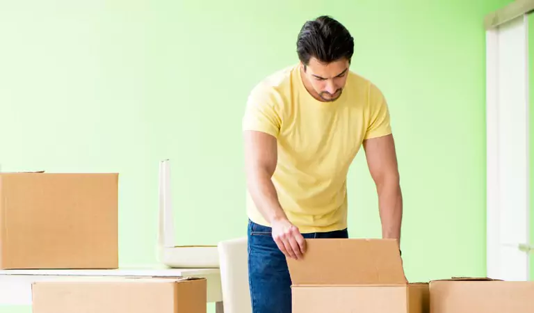 young muscular man unpacking a cardboard box