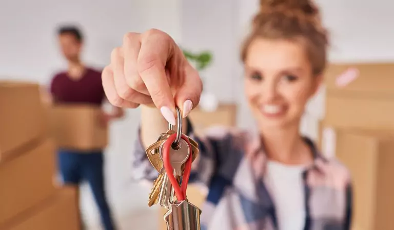 woman showing the keys of her new house and a young man at the back