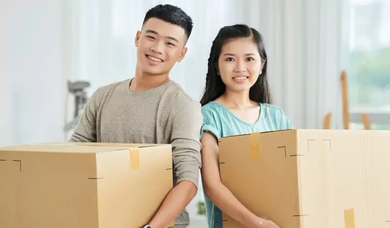 young couple holding heavy moving boxes
