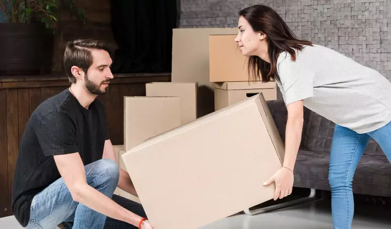 couple trying to lift a heavy cardboard box