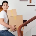 Young man climbing upstairs with a couple of cardboxes