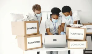 Guy and girl with check boxes volunteers in masks with laptop boxes with humanitarian aid